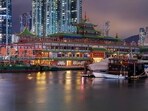 This long-exposure photo taken on June 12, 2022 shows the Jumbo Floating Restaurant located in the typhoon shelter near Aberdeen on the south side of Hong Kong island, partially boarded up in preparation for a reported voyage out of the city. - Local newspapers have reported the restaurant, which has been closed due to Covid-19 and lack of tourists since 2020, will exit the city after its owner suffered extensive losses.  (Photo by Daniel SUEN / AFP)