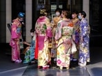 Women clad in a tradition Japanese kimonos are pictured standing by a building's entrance during the Women clad in a tradition Japanese kimonos are pictured standing by a building's entrance during the