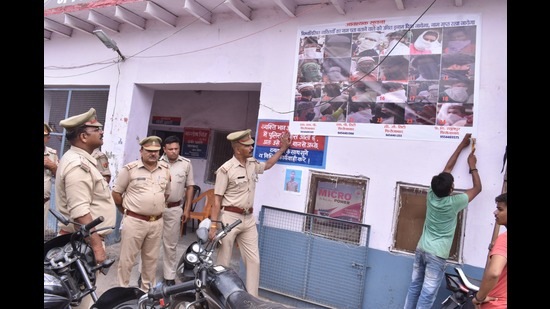 Cops pasting posters of suspects involved in Friday protests in Firozabad. (HT Photo)