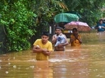 Commuters wade through a waterlogged area following heavy rain in Guwahati.