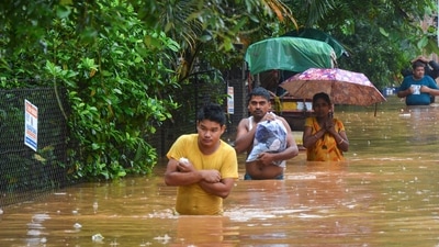 Commuters wade through a waterlogged area following heavy rain in Guwahati. (PTI) Commuters wade through a waterlogged area following heavy rain in Guwahati. (PTI)