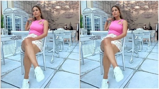 Hina paired a sleeveless pink cropped top with a short white skirt with multicolour prints and a belt detail at the waist.(Instagram/@realhinakhan)