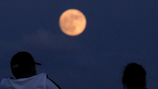 People watch the rising moon Monday, June 13, 2022, in East Boston, Mass. (Representational image)(AP)