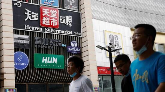 People walk past a sign of the Heaven Supermarket bar, where a Covid-19 outbreak emerged, in Chaoyang district of Beijing, China. (REUTERS)