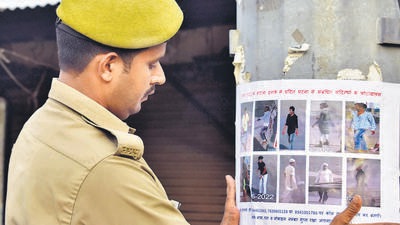 A policeman pastes a poster of alleged accused in Prayagraj violence, on Wednesday. (Anil Kumar Maurya/HT)