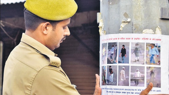 A policeman pastes a poster of alleged accused in Prayagraj violence, on Wednesday. (Anil Kumar Maurya/HT)