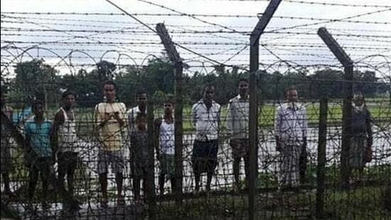 Indische Dorfbewohner außerhalb des Zauns entlang der internationalen Grenze zwischen Indien und Bangladesch in der Nähe von Karimganj in Assam warten darauf, dass die Grenzsicherheitskräfte die Tore öffnen.  (HT-Foto)
