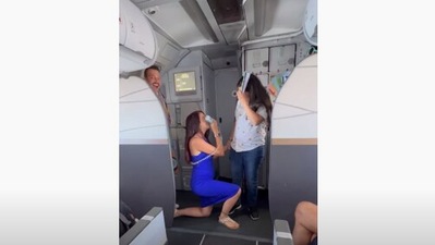 The image shows the flight attendant proposing to her pilot girlfriend aboard a special pride-themed plane. (YouTube/@Alaska Airlines)