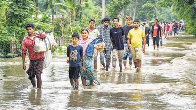 Villagers wade through a flooded road following heavy rainfall in Assam’s Kamrup district on Friday. (PTI)
