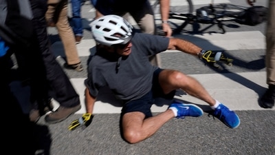 U.S. President Joe Biden falls to the ground after riding up to members of the public during a bike ride in Rehoboth Beach, Delaware. (REUTERS)