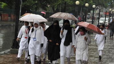 Girls walk with umbrellas on a rainy day in Srinagar on Saturday. A fresh landslide, triggered by rains on Saturday blocked Jammu-Srinagar national highway in Udhampur district. (Waseem Andrabi/HT)