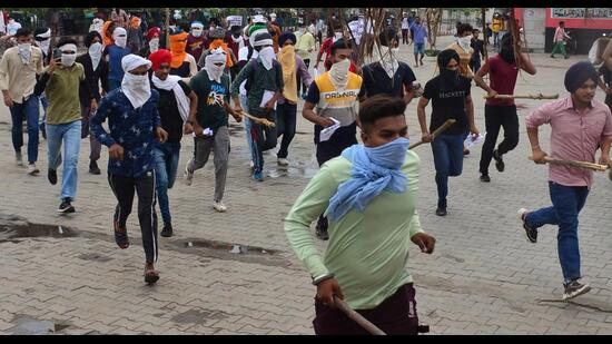 Armed with sticks and faces covered, youths rushing towards to the entrance of Ludhiana railway station, where they later burnt a block hut and vandalised furniture, on Saturday during a protest against Agnipath scheme. (Gurpreet Singh/HT)