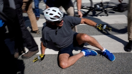 U.S. President Joe Biden falls to the ground after riding up to members of the public during a bike ride in Rehoboth Beach, Delaware.(REUTERS)