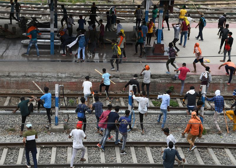 Protestors carrying sticks run at a railway station during a protest against the Agnipath scheme in Patna, Bihar. (Reuters)