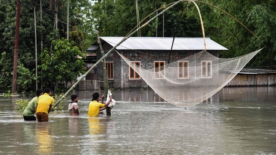 Villagers fish near a house submerged in flood waters along the national highway 31 in Rangia of Kamrup district, in Assam.(AFP)