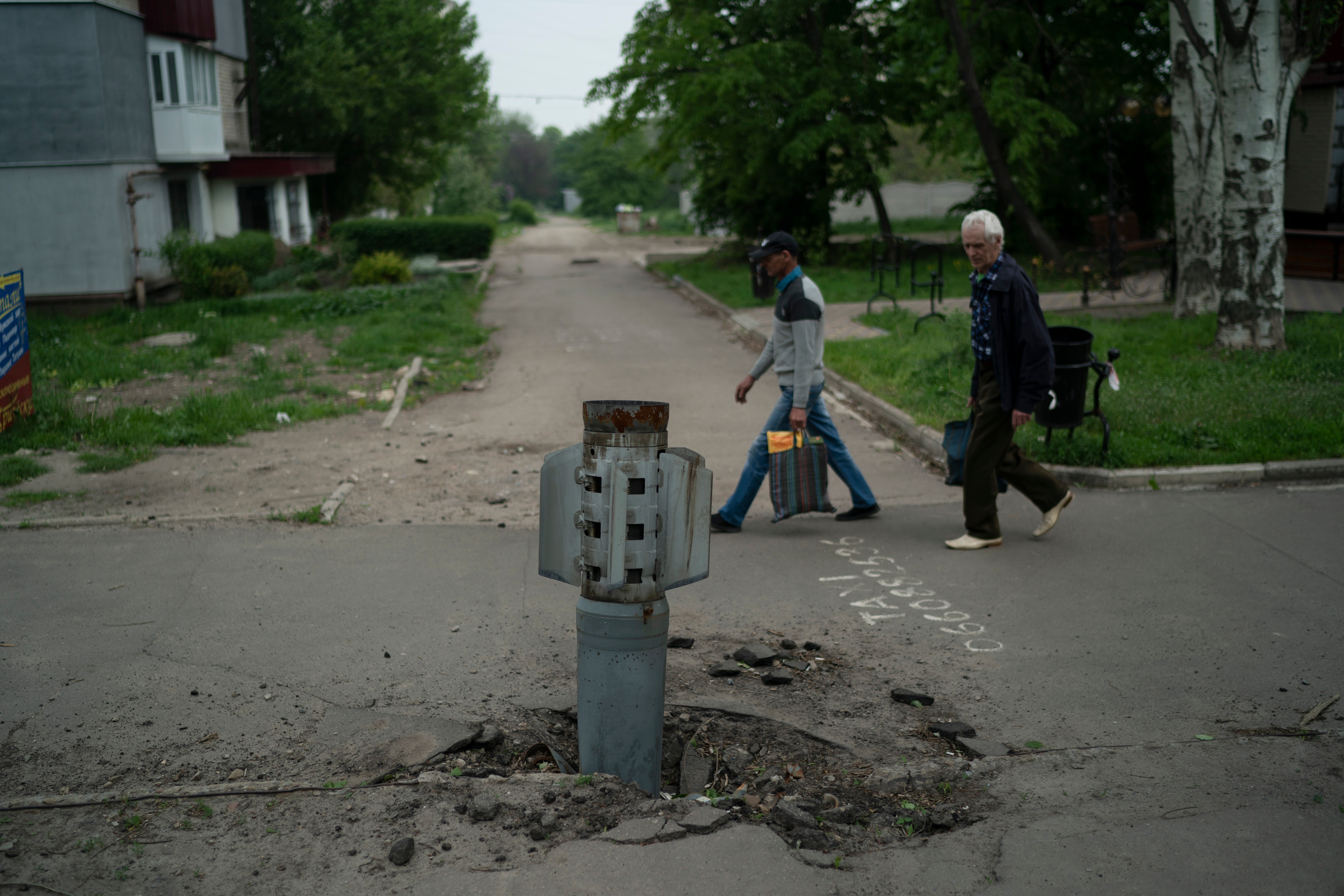 People walk past part of a rocket that sits wedged in the ground in Lysychansk, Luhansk region, Ukraine.&nbsp; (AP file photo)
