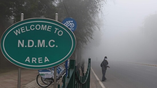 A commuter seen next to an NDMC signage at Tilak Marg in New Delhi on January 16. The minimum temperature is expected to be around 6-8 degrees Celsius and the maximum temperature could settle around 19 degrees Celsius on January 20.(Arvind Yadav / HT Photo)