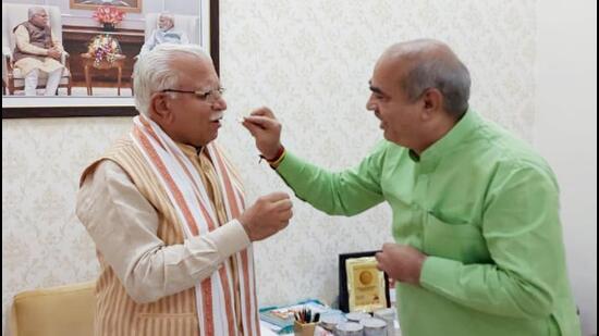 Haryana transport minister Mool Chand Sharma offers sweets to CM Manohar Lal Khattar after results. (HT Photo)