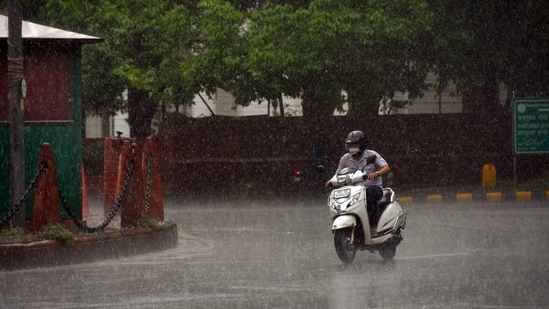 A man rides his scooty amid heavy showers of rain, at Kasturba Gandhi marg, in New Delhi on June 21.(ANI)