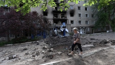 A woman walks past a shell crater in front of a damaged residential building in the town of Siversk, Donetsk region, amid Russia's military invasion launched on Ukraine.&nbsp; (AFP)