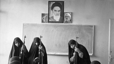 Basiji (mobilized volunteer force) women familiarise themselves with AK-47 assault rifles in a classroom in west Tehran as part of mass mobilisation in the final year of the Iran-Iraq war. This picture is dated 12 May 1988. (Kaveh Kazemi/Getty Images)
