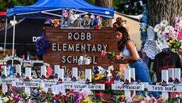 A girl lays flowers at a makeshift memorial at Robb Elementary School in Uvalde, Texas. (AFP)