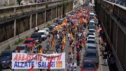 Manifestantes seguram uma faixa com os dizeres Abaixe as armas e aumente os salários, durante uma greve de transportes convocada pelo sindicato COBAS, no centro de Roma.