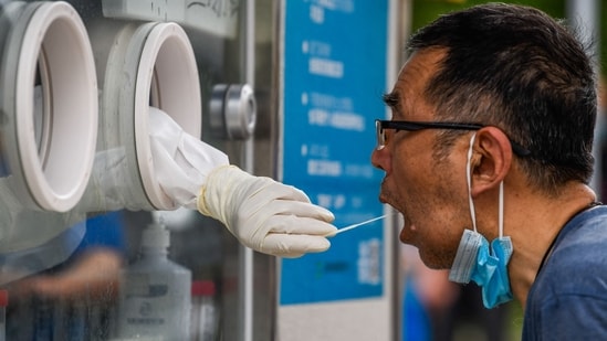 A health worker collects samples from a man to be tested for the Covid-19 coronavirus on a street in Shanghai's Huangpu district on June 22, 2022. (Photo by LIU JIN / AFP) / China OUT(AFP)