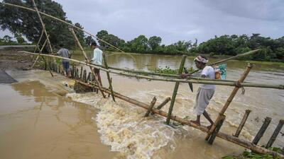 Villagers make a temporary bamboo bridge after a portion of a road was washed away due to floods following heavy rainfall, at a village in Nagaon in Assam on Sunday. (PTI PHOTO.) Villagers make a temporary bamboo bridge after a portion of a road was washed away due to floods following heavy rainfall, at a village in Nagaon in Assam on Sunday. (PTI PHOTO.)