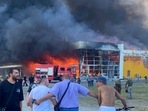 People watch as smoke bellows after a Russian missile strike hit a crowded shopping mall, in Kremenchuk, Ukraine. People watch as smoke bellows after a Russian missile strike hit a crowded shopping mall, in Kremenchuk, Ukraine.