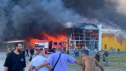 Pessoas assistem à fumaça após um ataque de míssil russo atingir um shopping lotado, em Kremenchuk, na Ucrânia.