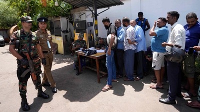 Army soldiers and a police officer secure a fuel station as people register themselves to purchase fuel in Colombo, Sri Lanka. (AP) Army soldiers and a police officer secure a fuel station as people register themselves to purchase fuel in Colombo, Sri Lanka. (AP)
