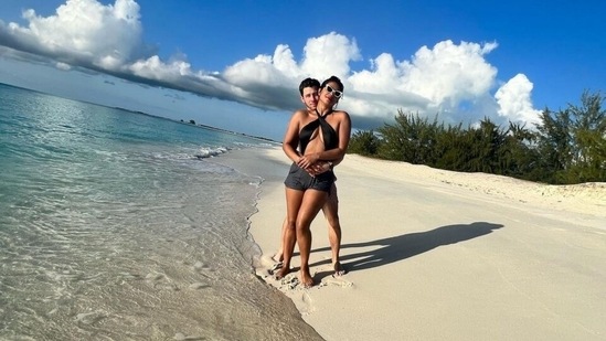 In this click, Nick hugged Priyanka from the back as they posed by the sea amid a scenic backdrop. The Matrix star looked glamorous in a black halter neck bikini top featuring a midriff-baring keyhole detail. She teamed it with a high bun, grey-coloured shorts and cat-eye black and white sunglasses.(Instagram)