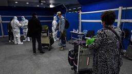 Passageiros, alguns com equipamento de proteção individual completo, esperando para serem transportados de ônibus para seus hotéis de quarentena, depois de chegarem ao Aeroporto Internacional de Pudong, em Xangai, em janeiro de 2022. (AFP)