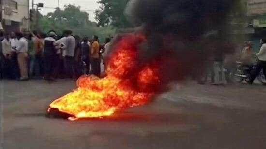 Smoke rises from a burning material while people gather on road as tensions rise after the killing of a tailor in Udaipur on Tuesday. (Reuters)