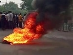 Smoke rises from a burning material while people gather on road as tensions rise after the killing of a tailor, in Udaipur on Tuesday. (Reuters)