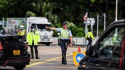 A polícia de trânsito direciona o tráfego perto da estação West Kowloon, em Hong Kong, na quinta-feira, quando o presidente chinês Xi Jinping chega a Hong Kong para participar das comemorações que marcam o 25º aniversário da transferência da cidade do Reino Unido para a China.  (AFP)