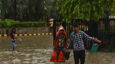 A young boy covers himself with a plastic sheet to protect him from the rain as he wades through flooded streets. (Vipin Kumar/ Hindustan Times)