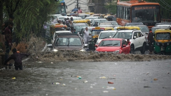 Commuters and vehicles wade through a waterlogged stretch in the National Capital Region..