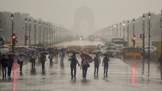 Pedestrians carry umbrellas on Rajpath during heavy rain in New Delhi.(Photo by (Raj K Raj/ Hindustan Times))