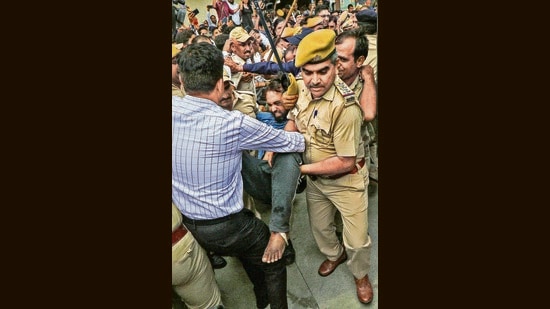 Police take an accused in the Kanhaiya Lal murder case away from the angry crowd outside the NIA court in Jaipur, on Saturday. (PTI)