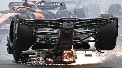 The overturned car of Alfa Romeo's Zhou Guanyu skids through the gravel after a crash at the start of the British Grand Prix. (AFP)