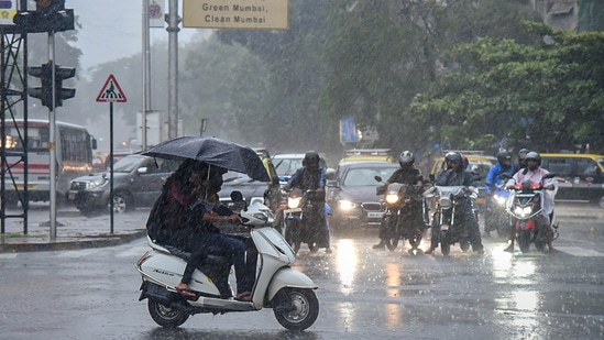 Commuters move on a road amid monsoon rains, in Mumbai.(PTI)