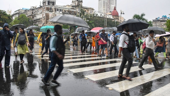 People holding umbrellas take a stroll amid monsoon rains.(PTI)
