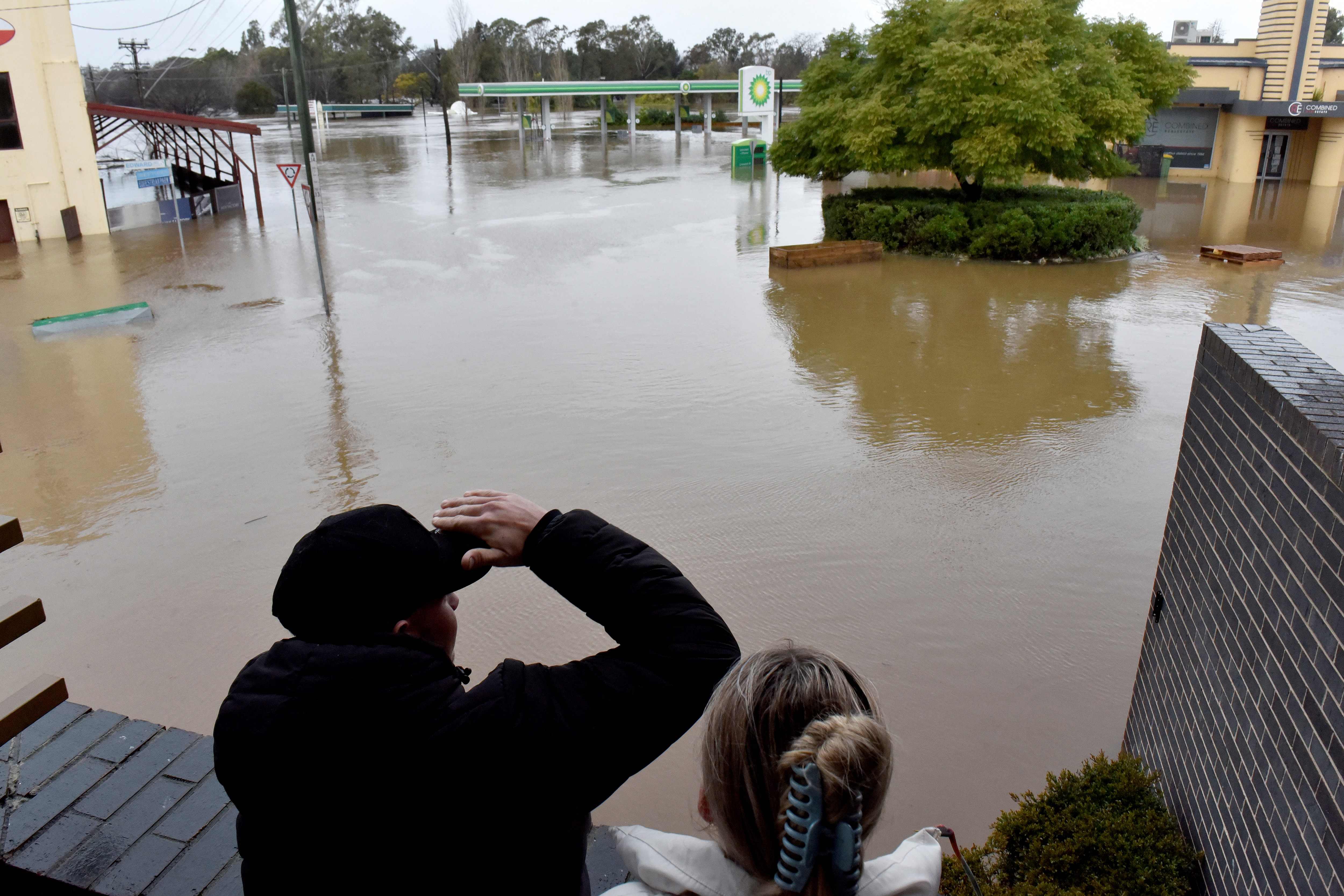 People look at flooded streets due to torrential rain in the Camden suburb of Sydney on July 3, 2022. (AFP) People look at flooded streets due to torrential rain in the Camden suburb of Sydney on July 3, 2022. (AFP)