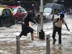 People navigate their way through a water logged street during heavy rainfall in Mumbai.(AP)