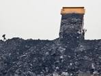 A worker keeps watch as a truck unloads coal in the village of Rajapur. A worker keeps watch as a truck unloads coal in the village of Rajapur.
