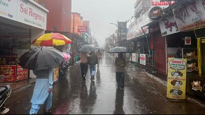 Tourists seen with umbrellas in the market area as heavy rains lash Mahabaleshwar on Tuesday. (HT PHOTO)