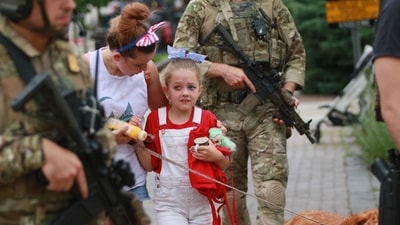 Law enforcement escorts a family away from the scene of a shooting at a Fourth of July parade on July 4 in Highland Park, Illinois. Police have detained Robert Bobby E. Crimo III, 22, in connection with the shooting. (AFP)