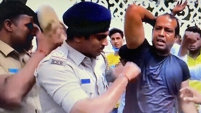 Policemen overpower Zameer Ahmed's supporter who poured kerosene oil on himself. (Twitter/ANI) Policemen overpower Zameer Ahmed's supporter who poured kerosene oil on himself. (Twitter/ANI)